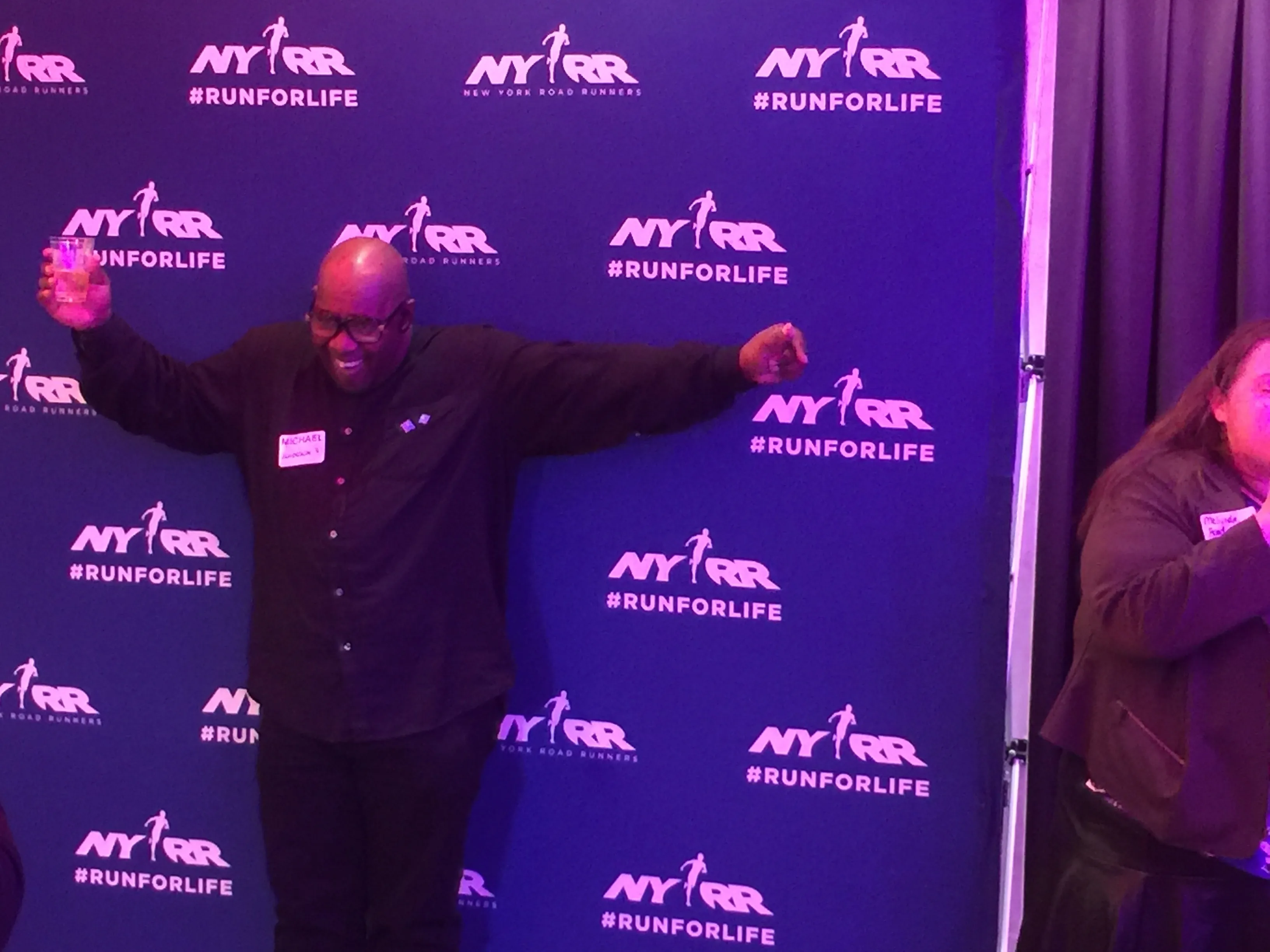 Singer at a weekly karaoke night in NYC with neon backdrop